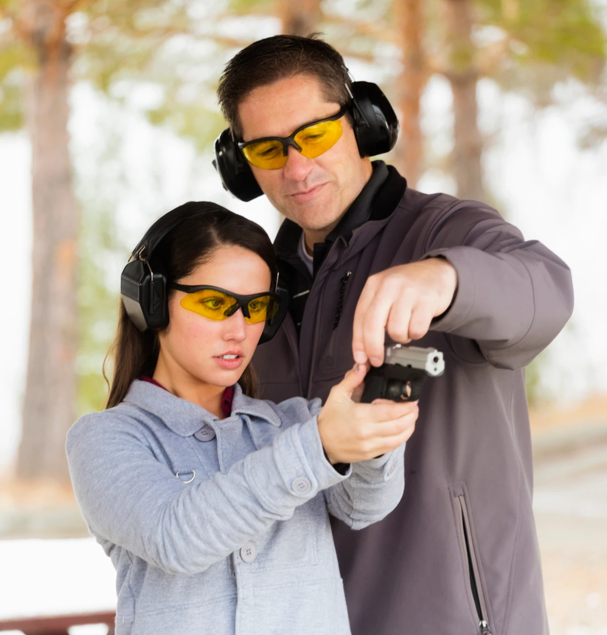 Man teaching woman to use handgun safely.