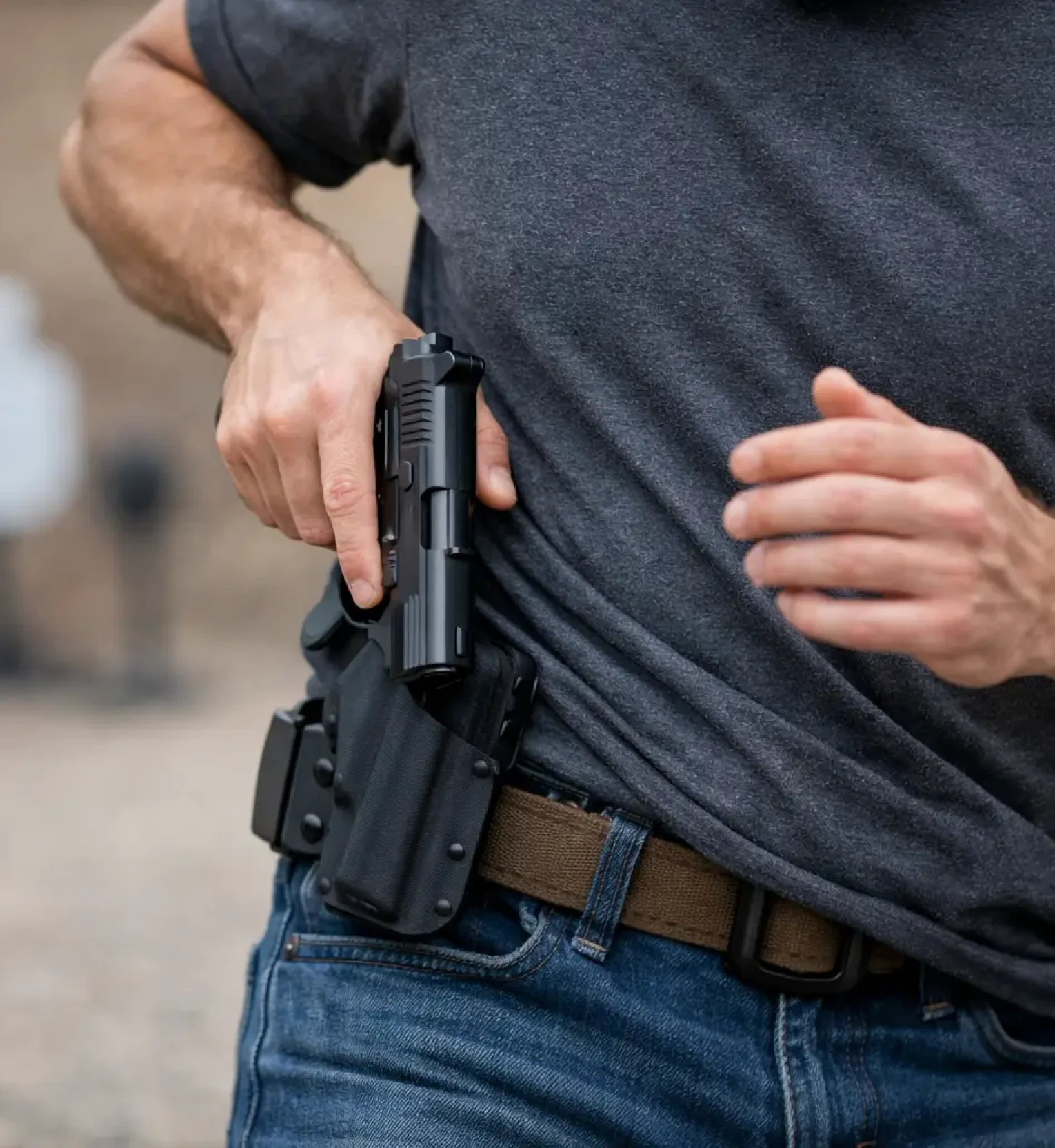 Person drawing handgun from hip holster.